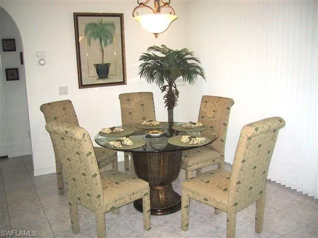 Dining area featuring arched walkways and tile patterned flooring