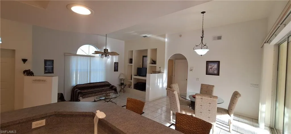 Dining area featuring arched walkways, light tile patterned floors, and a chandelier