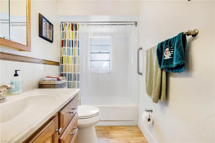 Full bathroom featuring hardwood / wood-style flooring, vanity, toilet, and shower / tub combo with curtain
