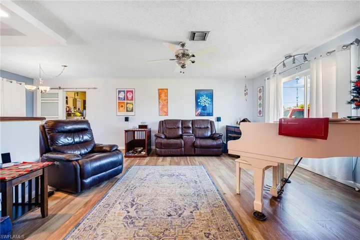 Living room with ceiling fan with textured ceiling, and hardwood / wood-style flooring