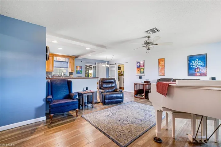 Living room featuring ceiling fan with  wood-type flooring, and a textured ceiling