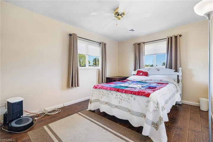 Bedroom with ceiling fan, dark hardwood / wood-style flooring, and multiple windows