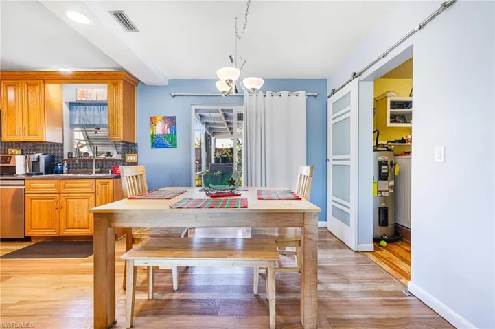 Dining room featuring a barn door, light hardwood / wood-style floors, a wealth of natural light, and water heater