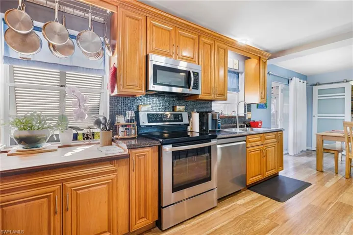 Kitchen featuring appliances with stainless steel finishes, dark stone counters, sink, a barn door, and light hardwood / wood-style floors