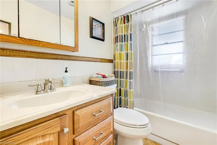 Full bathroom with shower / bath combo, toilet, tile walls, and vanity