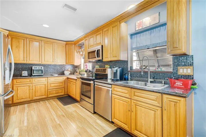 Kitchen featuring tasteful backsplash, sink, stainless steel appliances, and light hardwood / wood-style flooring