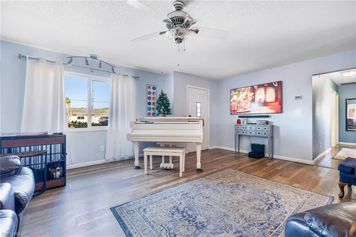 Living room featuring hardwood / wood-style floors, ceiling fan, and a textured ceiling
