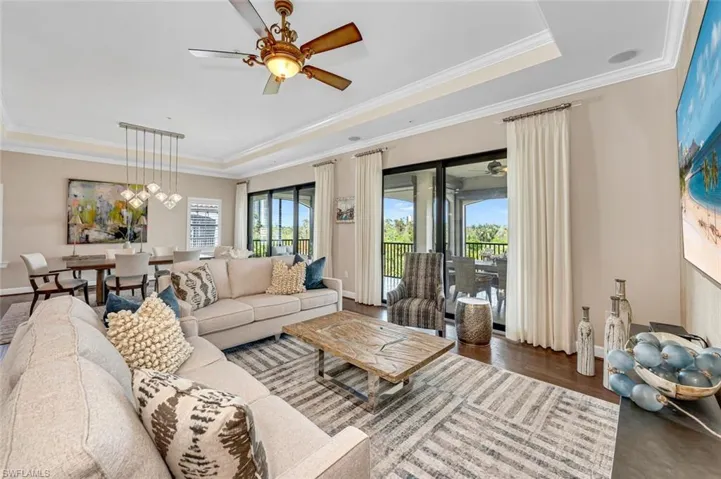 Living room featuring dark hardwood / wood-style floors, ceiling fan, ornamental molding, and a tray ceiling