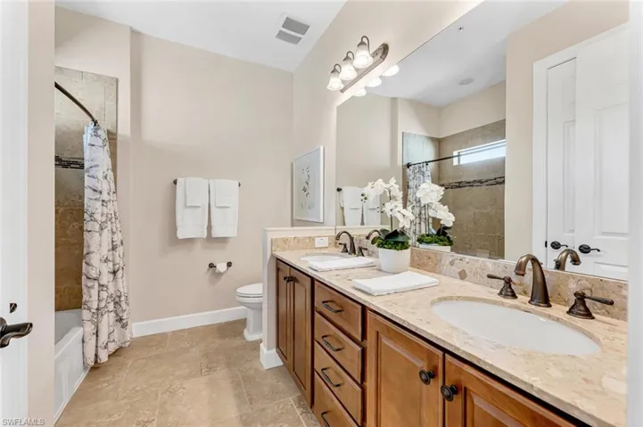 Full bathroom with shower / tub combo with curtain, vanity, and toilet