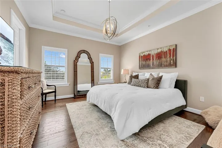 Bedroom featuring ornamental molding, dark hardwood / wood-style floors, a notable chandelier, and a tray ceiling