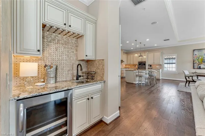 Kitchen featuring wine cooler, ornamental molding, sink, and pendant lighting