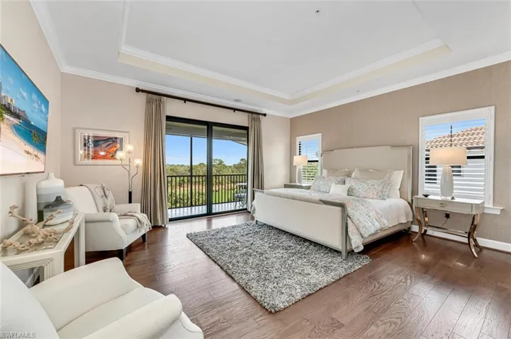 Bedroom featuring a tray ceiling, dark wood-type flooring, access to outside, and ornamental molding