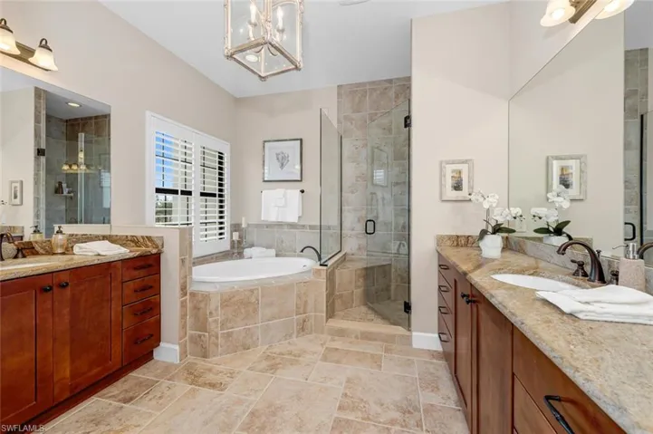 Bathroom with vanity, a notable chandelier, and separate shower and tub
