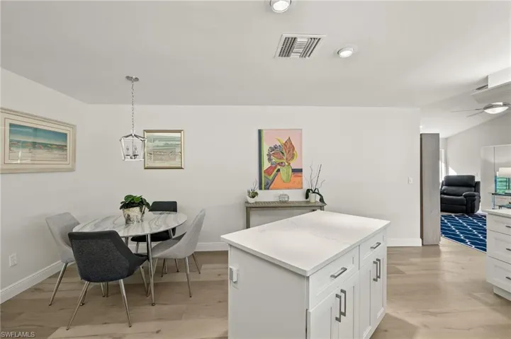Kitchen featuring a center island, decorative light fixtures, white cabinets, light hardwood / wood-style floors, and ceiling fan