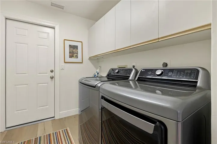 Laundry room with washer and dryer, cabinets, and light hardwood / wood-style floors
