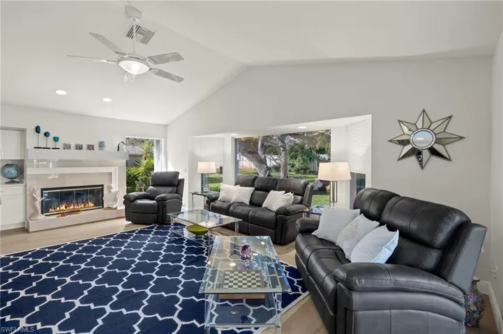 Living room with a healthy amount of sunlight, vaulted ceiling, a fireplace, and hardwood / wood-style floors