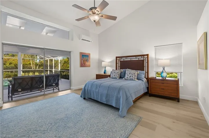 Bedroom featuring a wall mounted AC, multiple windows, access to outside, and ceiling fan
