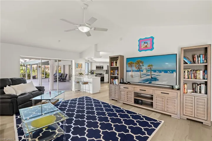 Living room featuring light hardwood / wood-style floors, lofted ceiling, and ceiling fan