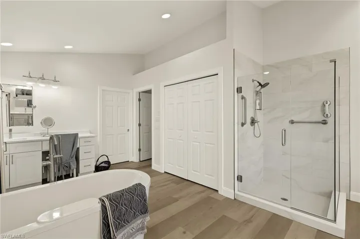 Bathroom with vanity, walk in shower, vaulted ceiling, and hardwood / wood-style floors