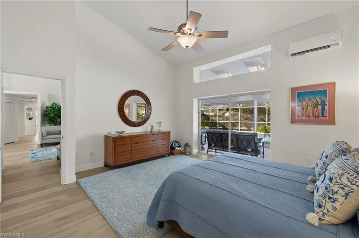 Bedroom with access to outside, light wood-type flooring, ceiling fan, a wall unit AC, and high vaulted ceiling