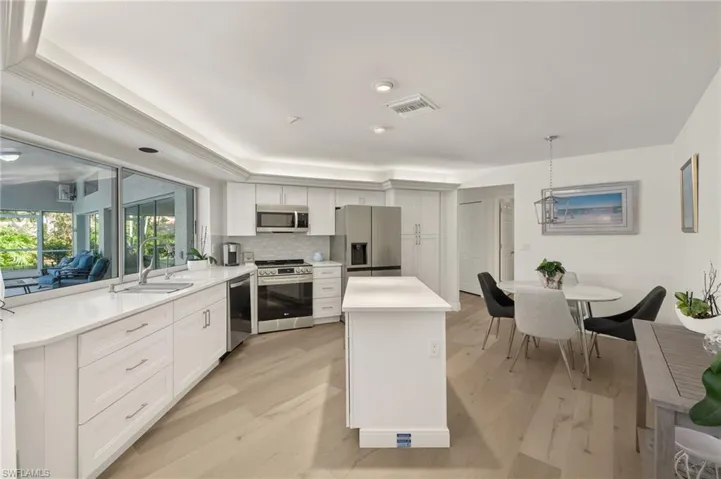 Kitchen with appliances with stainless steel finishes, white cabinets, sink, and pendant lighting