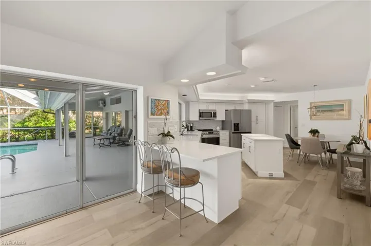 Kitchen with kitchen peninsula, backsplash, appliances with stainless steel finishes, white cabinetry, and a kitchen bar