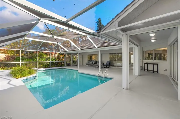 View of pool with a patio area and glass enclosure