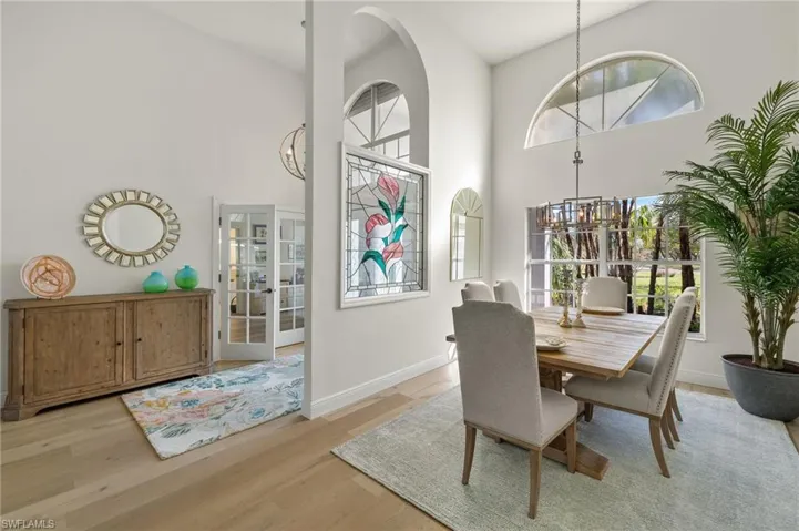 Dining room featuring a towering ceiling, an inviting chandelier, light wood-type flooring, and a healthy amount of sunlight