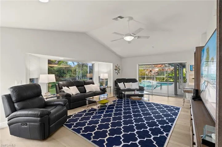 Living room with ceiling fan, wood-type flooring, and lofted ceiling