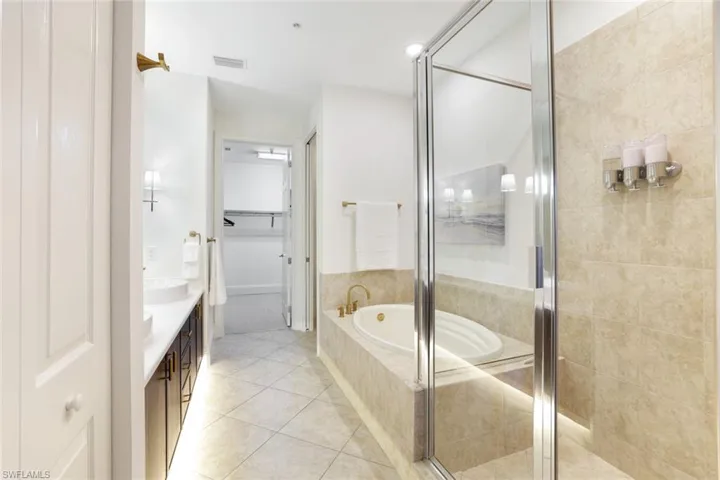 Full bathroom with a spacious closet, vanity, a bath, a stall shower, and light tile patterned floors