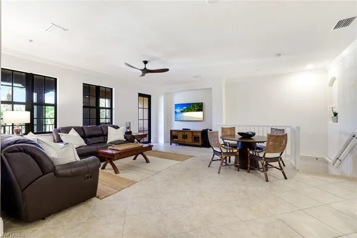 Living room with ceiling fan, ornamental molding, and light tile patterned floors