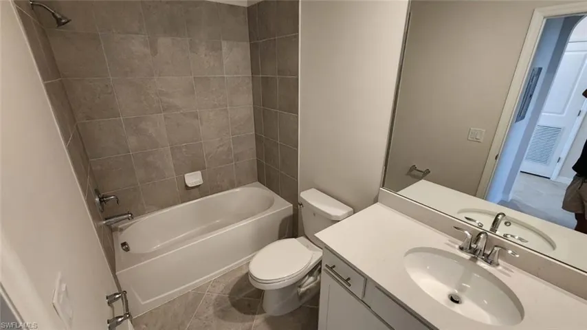 Bathroom featuring a white vanity with an integrated sink, polished chrome faucet, and expansive mirror