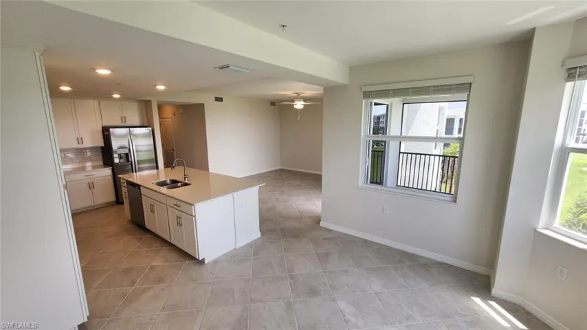 Kitchen featuring an island with double sinks, white cabinetry, integrated stainless steel appliances, a tile backsplash, and recessed lighting