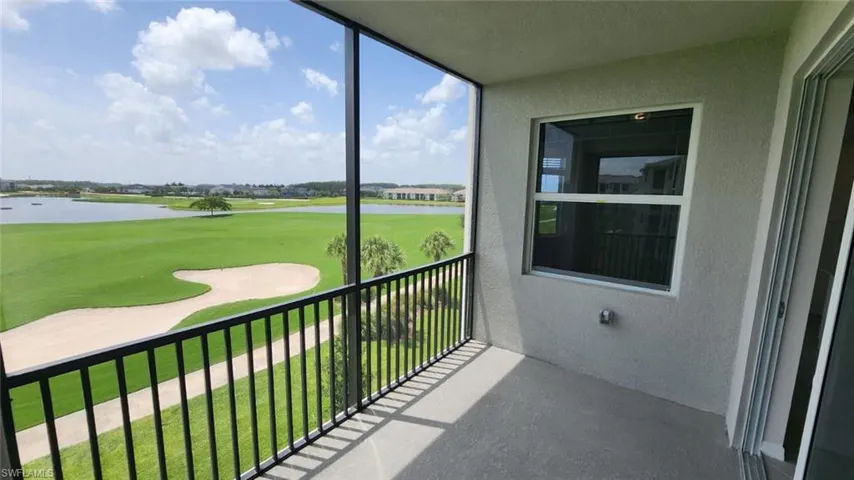 Screened balcony overlooking a golf course with a prominent sand trap and water feature