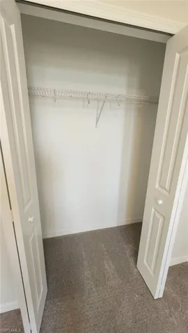 Interior closet with bi-fold paneled doors, wire shelving, and carpeting