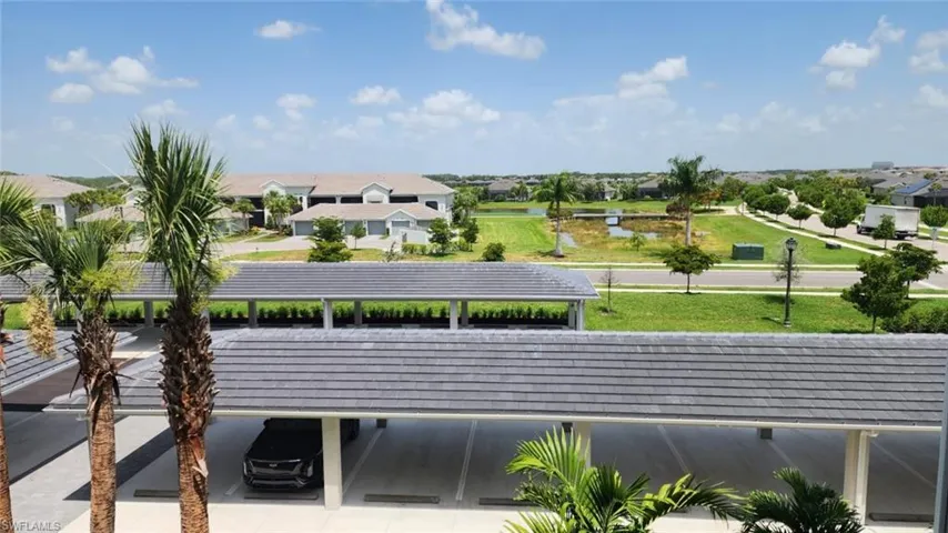 Covered parking structure with tile roofing, surrounded by lush tropical landscaping and palm trees