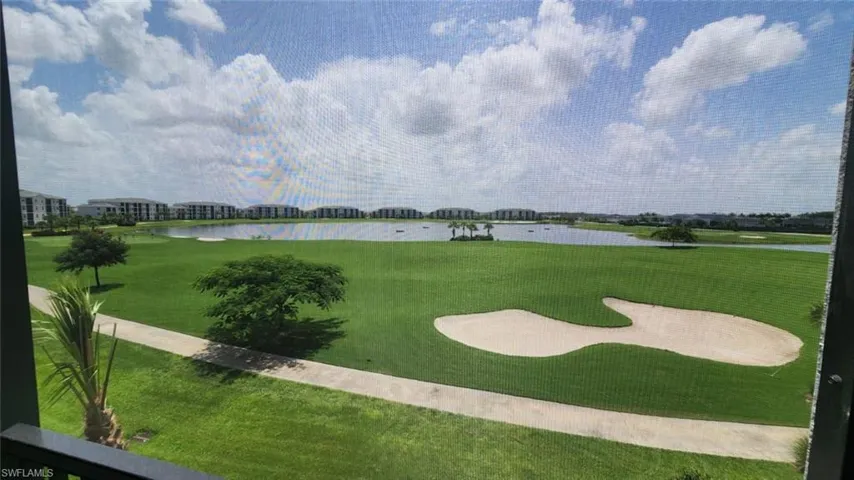 Expansive golf course frontage with a manicured green, sand traps, and a winding cart path