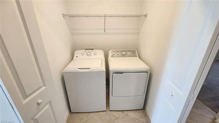 Dedicated laundry area featuring tile flooring and a wire shelving unit