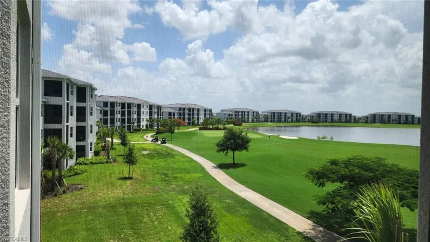 Expansive golf course frontage with a water feature, bordered by multi-story residential buildings featuring screened balconies