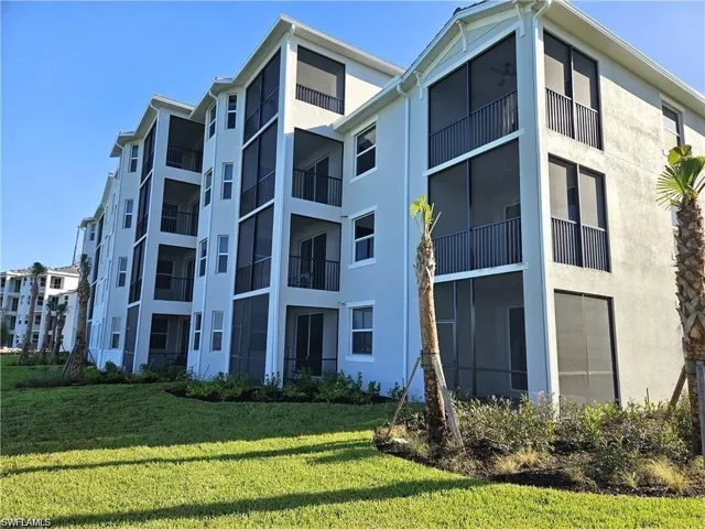 Multi-story building featuring light-toned stucco exterior, black screened balconies, black balcony railings, and white window frames