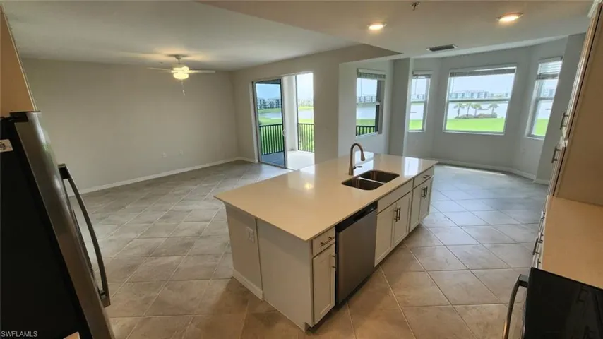 Open-concept living area featuring an expansive kitchen island with a double basin sink and stainless steel appliances