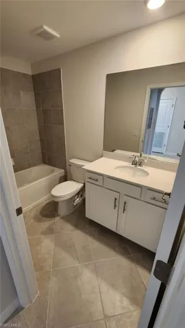 Bathroom featuring a single vanity with white cabinetry, a built-in sink, and a rectangular mirror