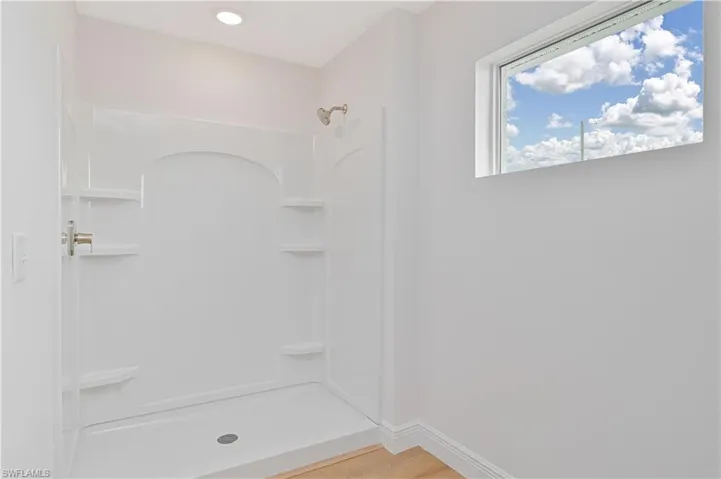 Full bath featuring a shower stall and light wood-style flooring