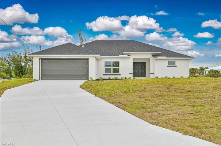 View of front of house featuring stucco siding, a front lawn, and a garage