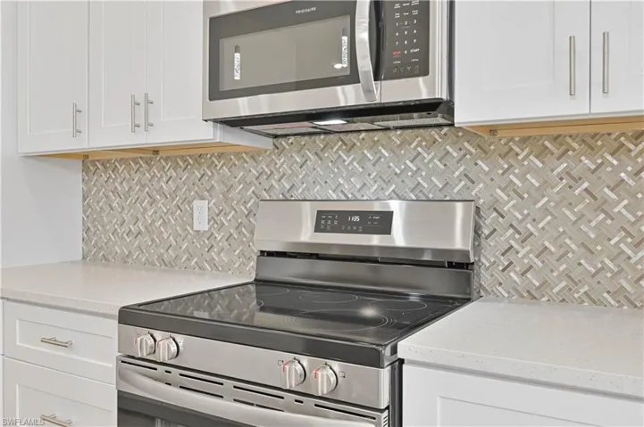 Kitchen with stainless steel appliances, white cabinets, and backsplash