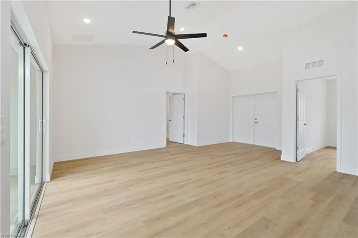 Unfurnished bedroom featuring two closets, ceiling fan, recessed lighting, light wood finished floors, and lofted ceiling