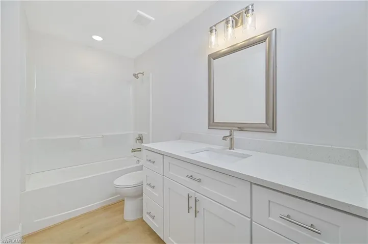 Full bathroom featuring vanity, light wood-style floors, tub / shower combination, and recessed lighting