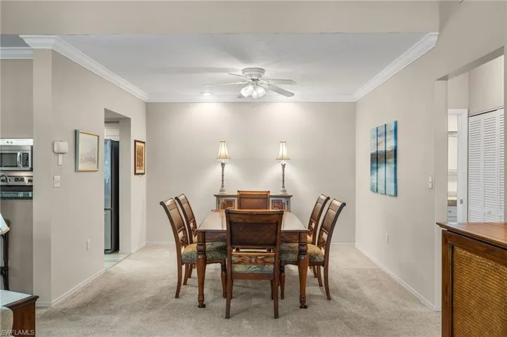 Dining space featuring crown molding, light carpet, and ceiling fan