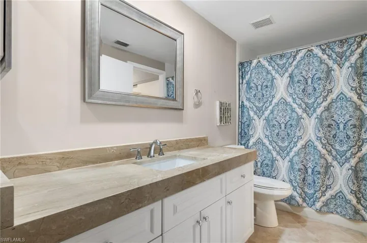 Bathroom with a shower with curtain, vanity, toilet, and tile patterned floors