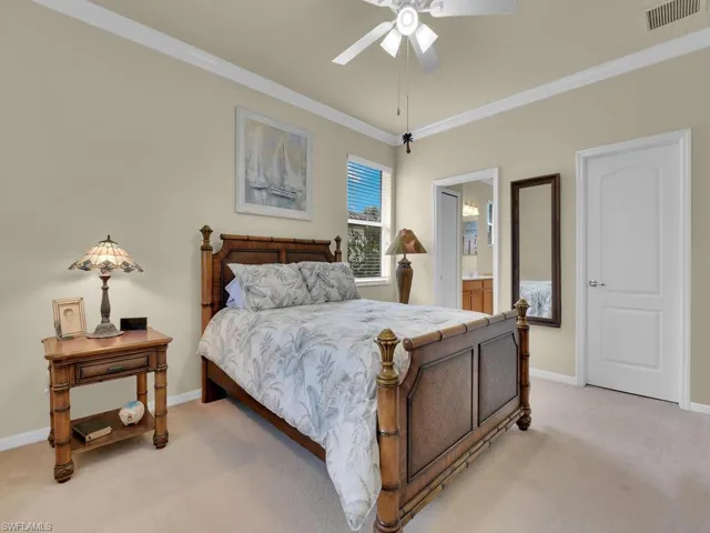 Carpeted bedroom with ensuite bath, ceiling fan, and crown molding